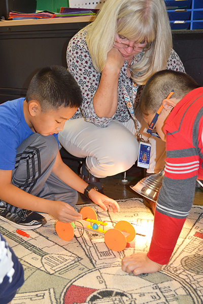 Fourth grade teacher Jennifer Simmons looks on as two of her students test their solar car.